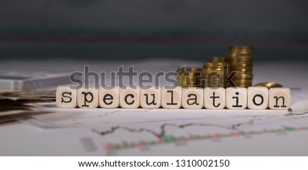 Word SPECULATION composed of wooden letter. Stacks of coins in the background. Closeup Royalty-Free Stock Photo #1310002150