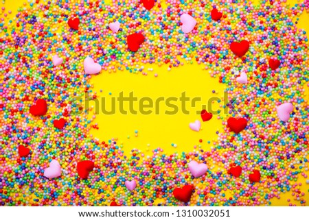 Beautiful background of hearts and colorful balls. Festive background of love and romance. Red and pink hearts are beautifully laid out on a yellow background. Valentine's Day. Copy space.