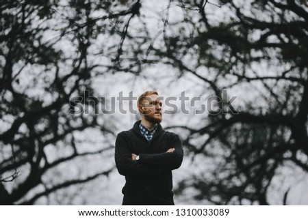 Portrait of handsome tall man standing outside in the thick autumn fog