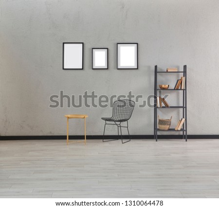 Grey stone wall background, many frame on the wall and bookshelf, chair and vase of plant.