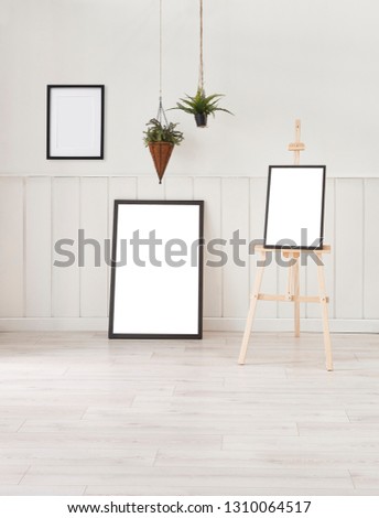 White room, frame and picture with vase of green flowers. Wooden decor background.