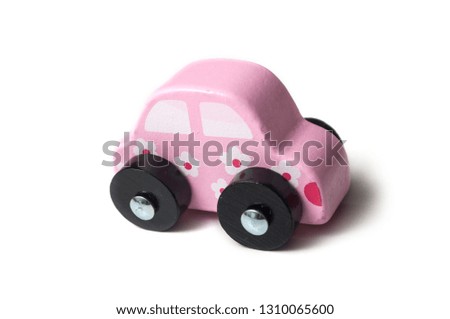 closeup of pink miniature wooden car on white background 
