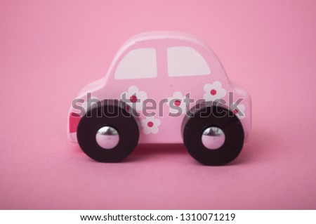 closeup of pink miniature wooden car on pink background 