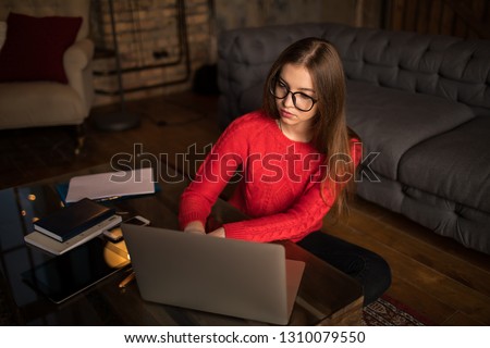 Top view of a stylish hipster girl experienced blogger typing article on laptop computer, sitting at coffee table with working tools indoors home interior.Female designer using applications on netbook