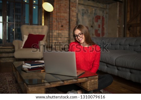 Charming happy smiling woman in glasses having online conference via laptop computer, sitting indoors home during recreation time. Joyful female having video call via notebook, resting after webinar  