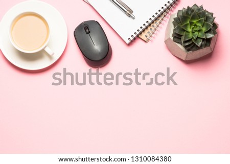 Office workplace with notepad, coffee cup, mouse and succulent on pink background. Flat lay image.