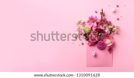 Pink envelope with spring flowers. Floral composition, creative layout. Flat lay, top view. Spring, summer or garden concept. Present for Woman day.