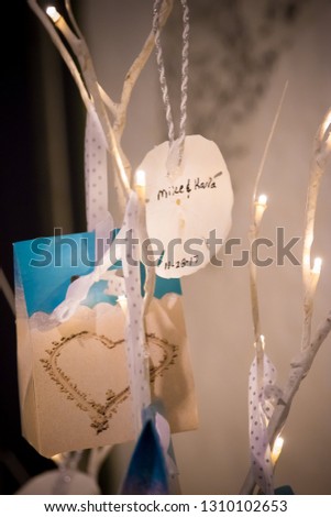 SandDollar hanging from a stick with a picture of a heart drawn in the sand in the background hanging by gray and white polka dot ribbon