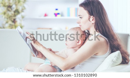 happy mother showing his year-old baby pictures on digital tablet