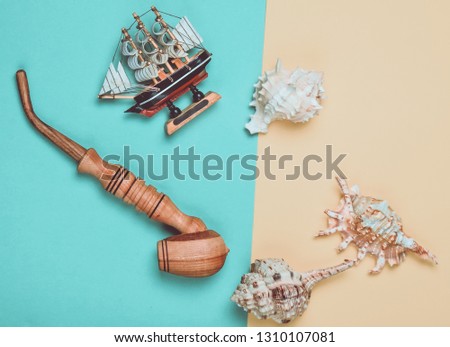 Decorative ship, seashells, chicken pipe on a colored pastel background. Captain shipwreck.  Summer Beach Concept. Top view, minimalism