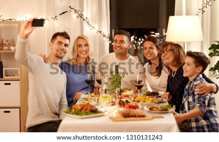 celebration, holidays and people concept - happy family having dinner party at home and taking selfie by smartphone