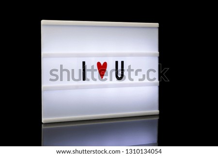 I love you, acronym written on lightbox reflected on black background