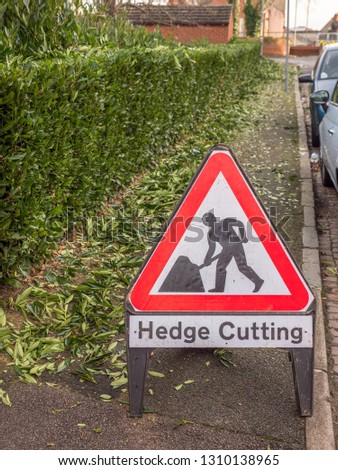 day view hedge cutting warning sign in English town