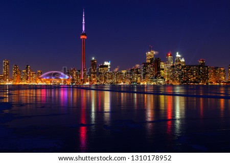 Toronto city skyline lights at night reflected on the frozen ice covered Lake Ontario