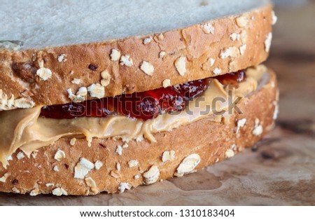 Homemade Peanut Butter and Jelly Sandwich on oat bread, over a rustic wooden background ready for lunch.