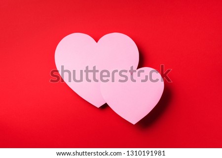 Two pink hearts cutted from paper over red background with copy space. Top view. Valentine's Day. Love, date, romantic concept