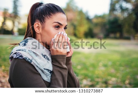 Cold and flu. Woman blowing her nose with a tissue Royalty-Free Stock Photo #1310273887