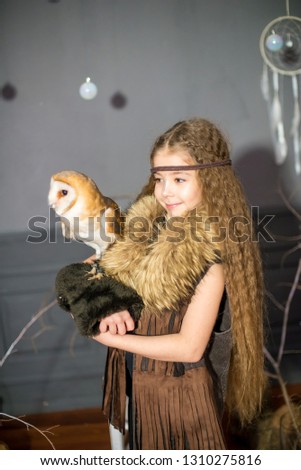 Cute girl with long hair with a white owl in her arms in the style of boho 
