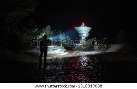 Men with tactical backpack lights up a huge radio telescope by flashlight in Irbene, Latvia Royalty-Free Stock Photo #1310319088