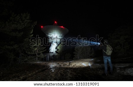 Men with tactical backpack lights up a huge radio telescope by flashlight in Irbene, Latvia Royalty-Free Stock Photo #1310319091