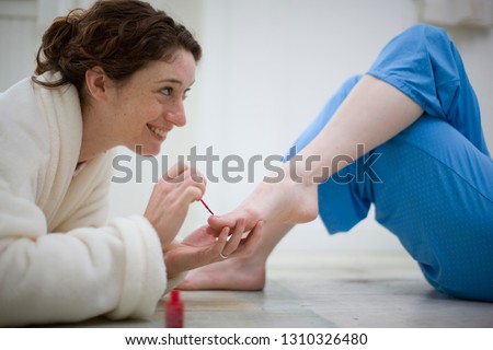 Couple painting toenails in house