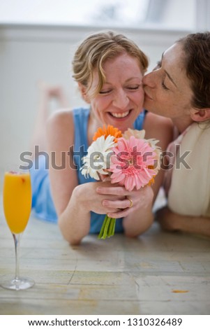 Women lying on floor in house with orange juice and flowers