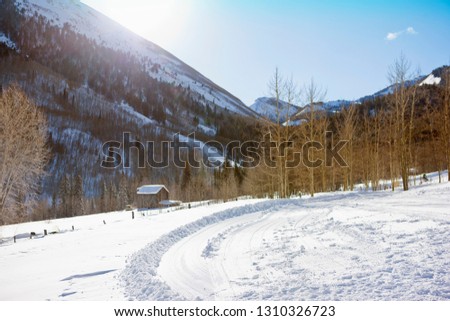 Log cabin covered in snow in a wintry landscape.