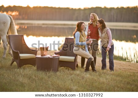 Woman relaxing with wine by a lake after a days horse riding