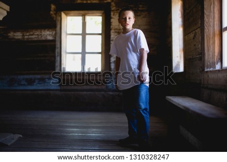 Boy standing in empty log cabin