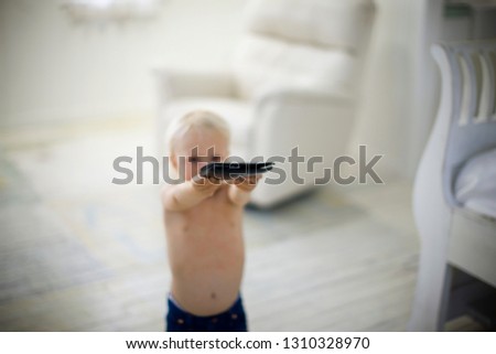 Portrait of a shirtless toddler holding up a wallet.