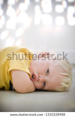 Portrait of a young boy lying with his head on the floor.