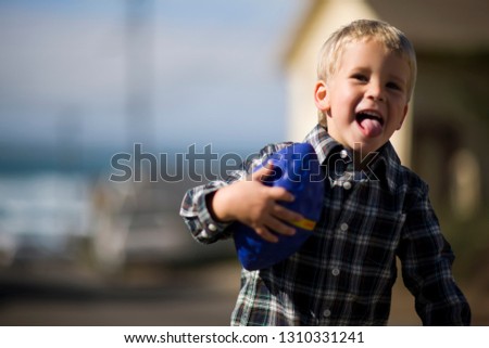 Portrait of a young boy playing outside with a toy football.