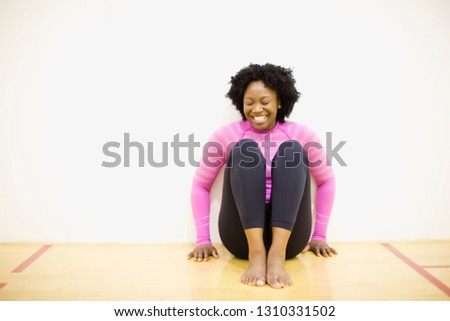Mid-adult woman sitting on the floor of a gym.