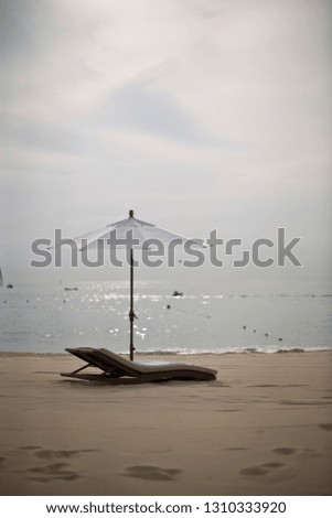 Empty lounger and sun umbrella on the beach at sunset