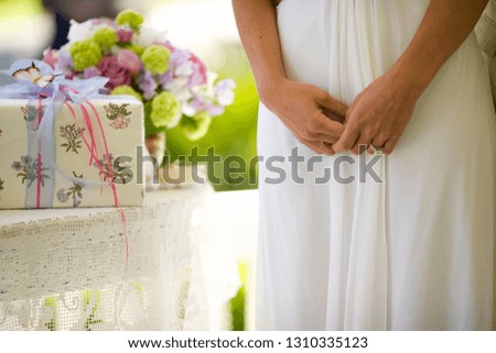 Engagement ring on a bride's hand standing beside a gift table.