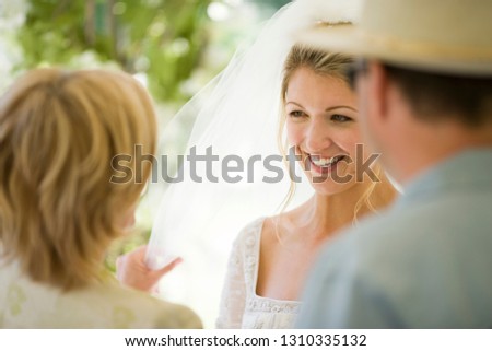 Young adult bride speaking to her mother and father.