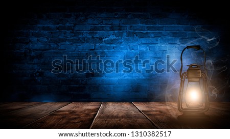 Magic night lantern. Night lantern on the background of an old brick wall, the magic glow of the lantern in the dark, wooden floor.