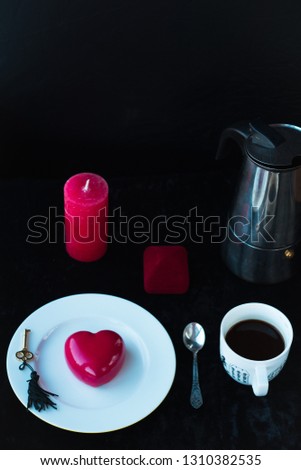 
Key from the female heart. dinner on Valentine's Day with a red heart mousse dessert, coffee and the idea of ​​making an offer to marry. Black background. romantic evening for a girl. Marry me idea.
