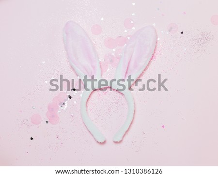 Top view and flat lay of Easter symbol - bunny ears on pink background. Festive and bright, confetti and sparks.