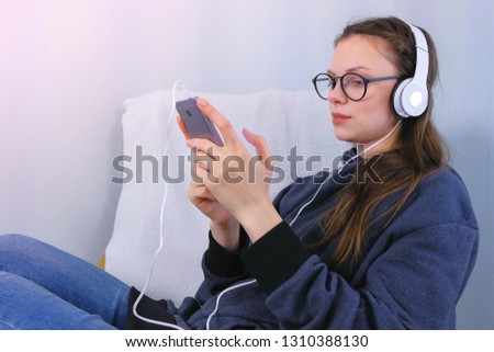 Woman listens music in headphones on smartphone and sings a song.