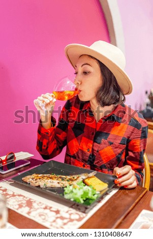 Woman eating fish and drinking wine in restaurant