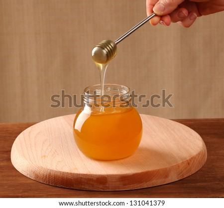 Pot of honey and steel dipper on a table