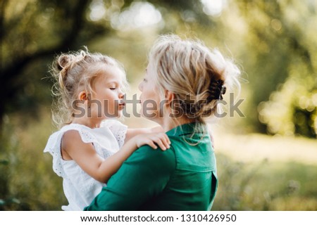 Young mother in nature holding small daughter in the arms.