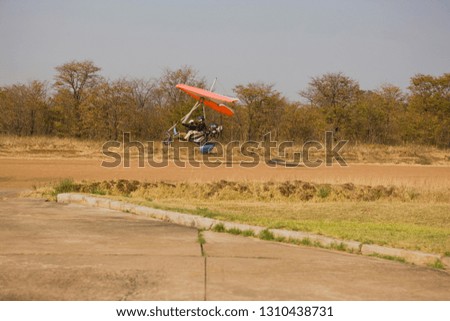 Micro light coming into land on a dusty runway.