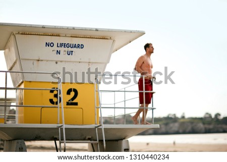 Lifeguard in lifeguard tower surveying the beach.