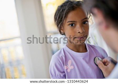 Concerned young girl has her heartbeat listened to by her family doctor.