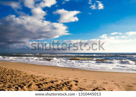 Autumn stormy sea on a sunny day with splashes from big waves. Large waves with white foam on the crest rise above the surface of the water and run to the shore. Background of beautiful nature