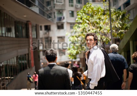 Businessman looking over his shoulder in a crowded street.