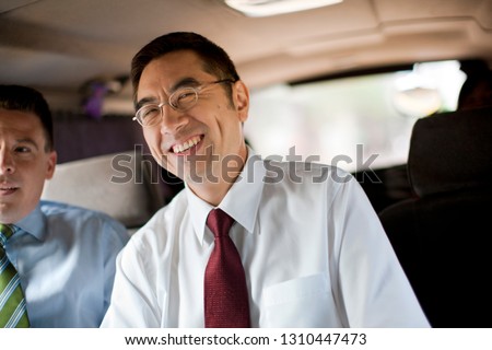 Two businessman sitting next to each other on a van.