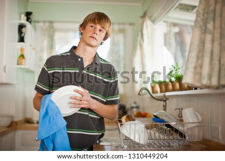 Teenage boy washing dishes in a kitchen.